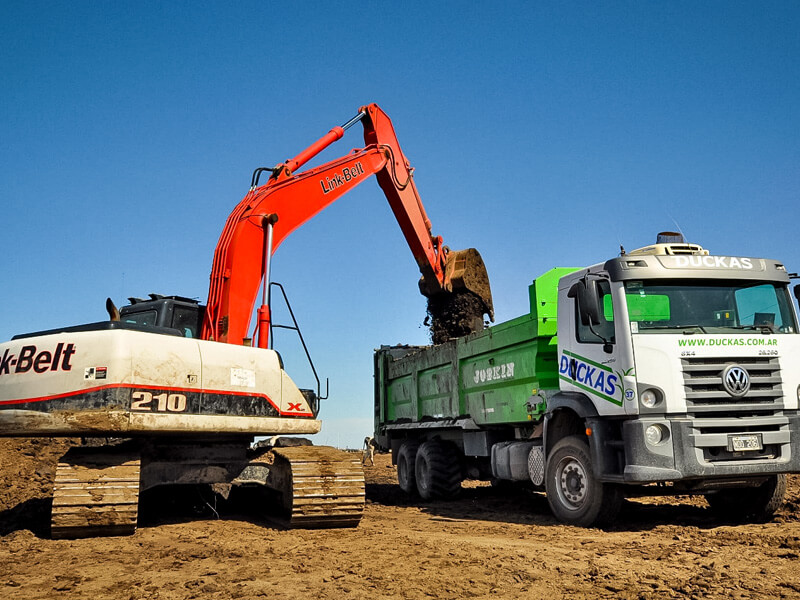 Foto de excavadora llenando un camión de volteo, trabajando en el campo argentino. Duckas Vial expertos en esparcido de fertilizante y movimiento de suelos